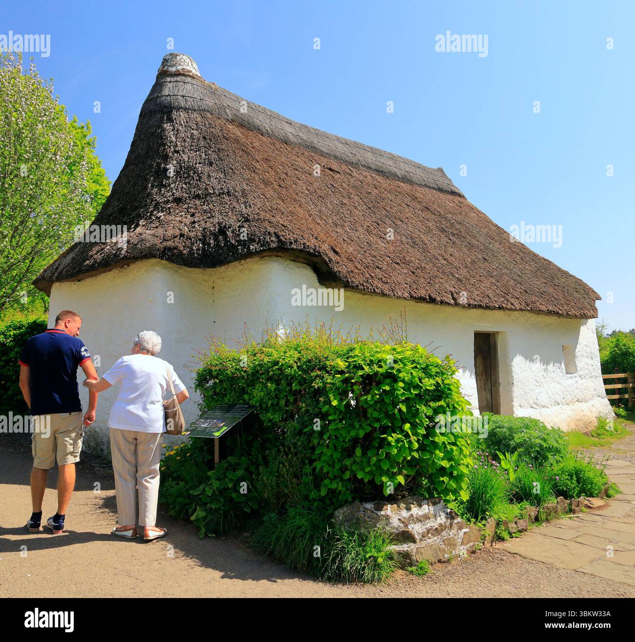 Mann und Frau, die Nantwallter-Strohhütte bewundern. St Fagans National Museum of History, Cardiff. Vom April 2025 Stockfoto