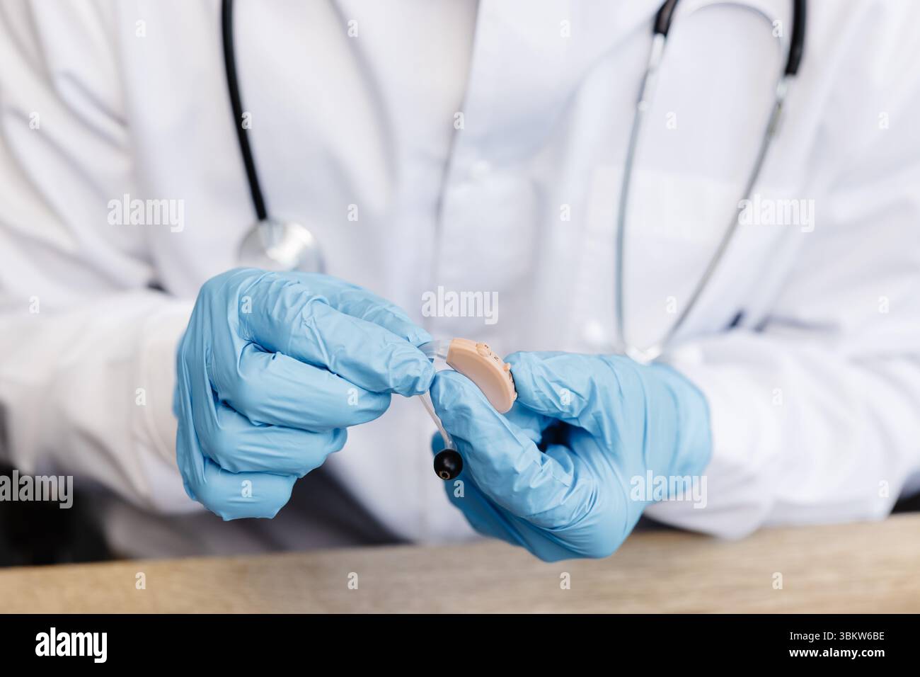 Ein HNO-Arzt hält ein Hörgerät in den Händen. Der Arzt konsultiert den Patienten. Stockfoto