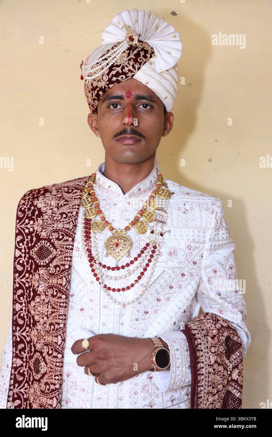 Traditioneller indischer Bräutigam posiert drinnen in Hochzeitskleidung Stockfoto