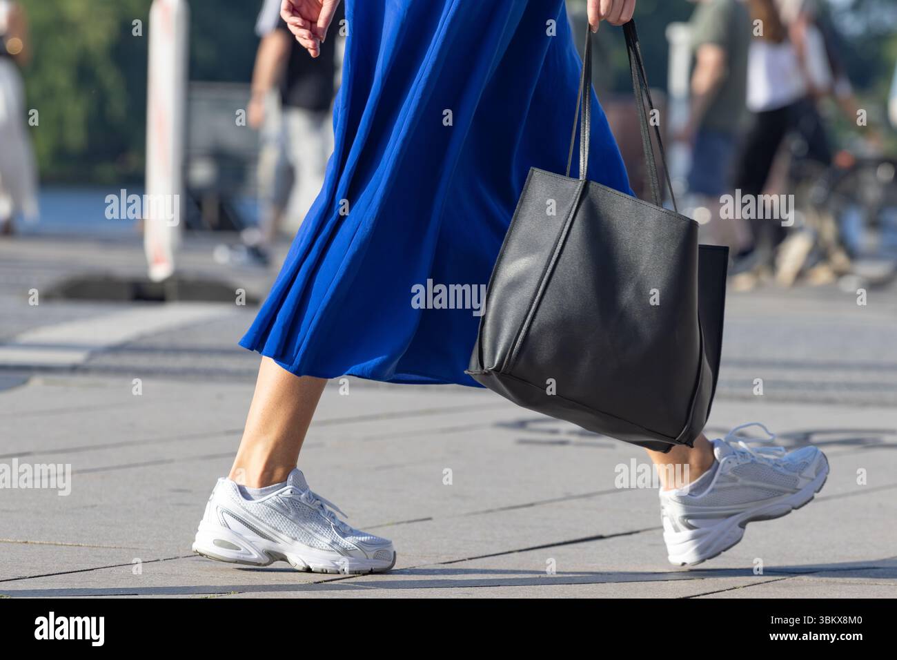 Frau mit blauem Kleid und schwarzer Ledertasche Stockfoto