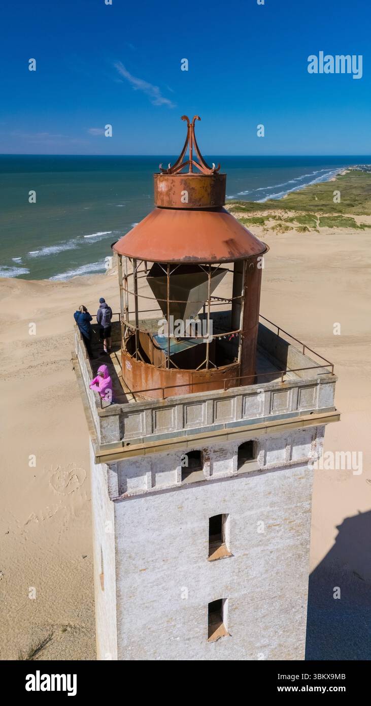 Besucher bewundern die atemberaubende Aussicht vom Leuchtturm Rubjerg Knude, einem historischen Wahrzeichen mit Blick auf die Sandstrände und Dünen Dänemarks. Stockfoto