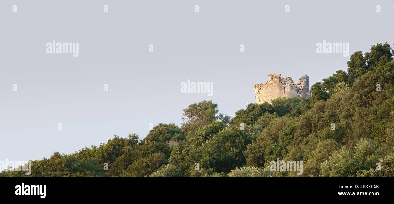 Landschaftspanorama einer ruinösen Windmühle, die oberhalb der Baumlinie an einem steilen geneigten Horizont erscheint, Kefalonia, Griechenland Stockfoto