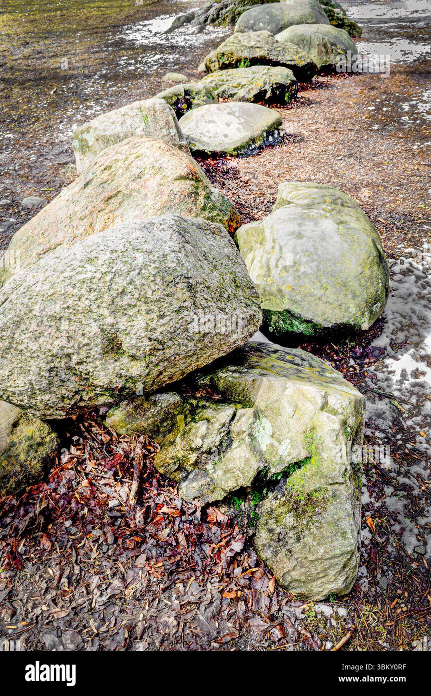Nahaufnahme einer Reihe von Steinen neben leichtem Schnee auf einem Feld Stockfoto