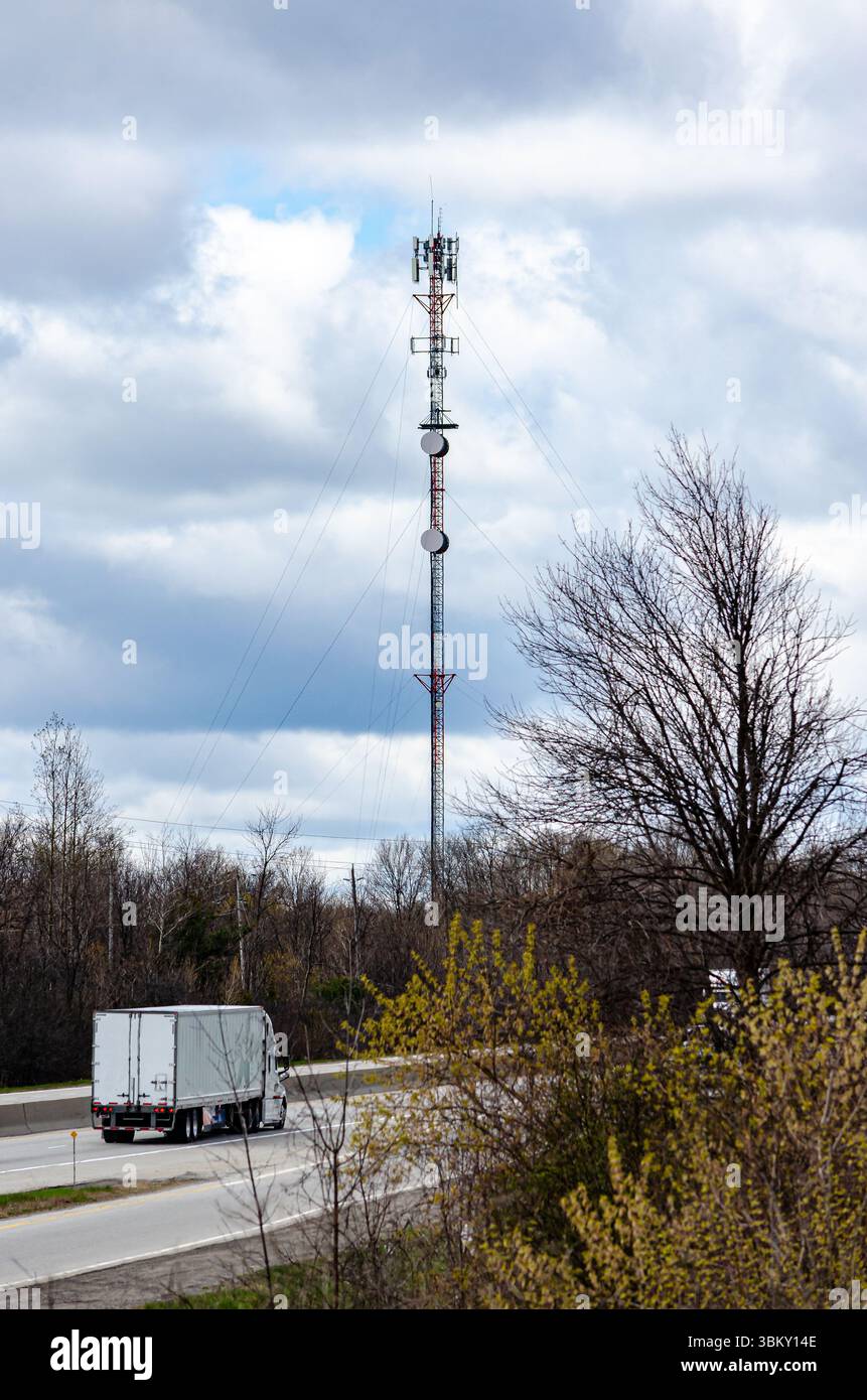 Transporter auf der Autobahn neben einem Kommunikationsturm vor einem bewölkten blauen Himmel. Stockfoto