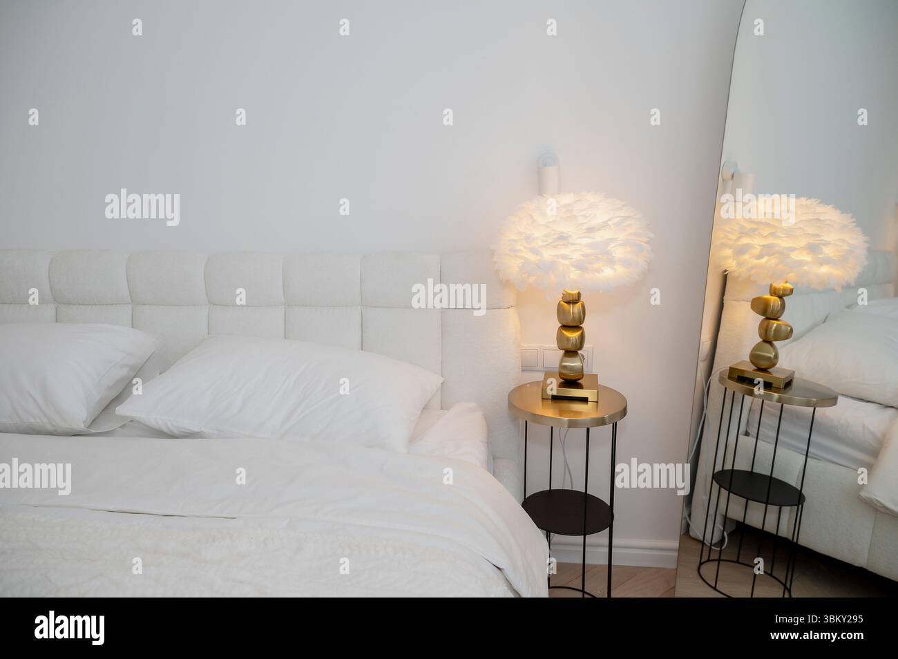 Innenraum des Schlafzimmers mit moderner Leselampe auf dem Tisch neben dem Doppelbett Stockfoto