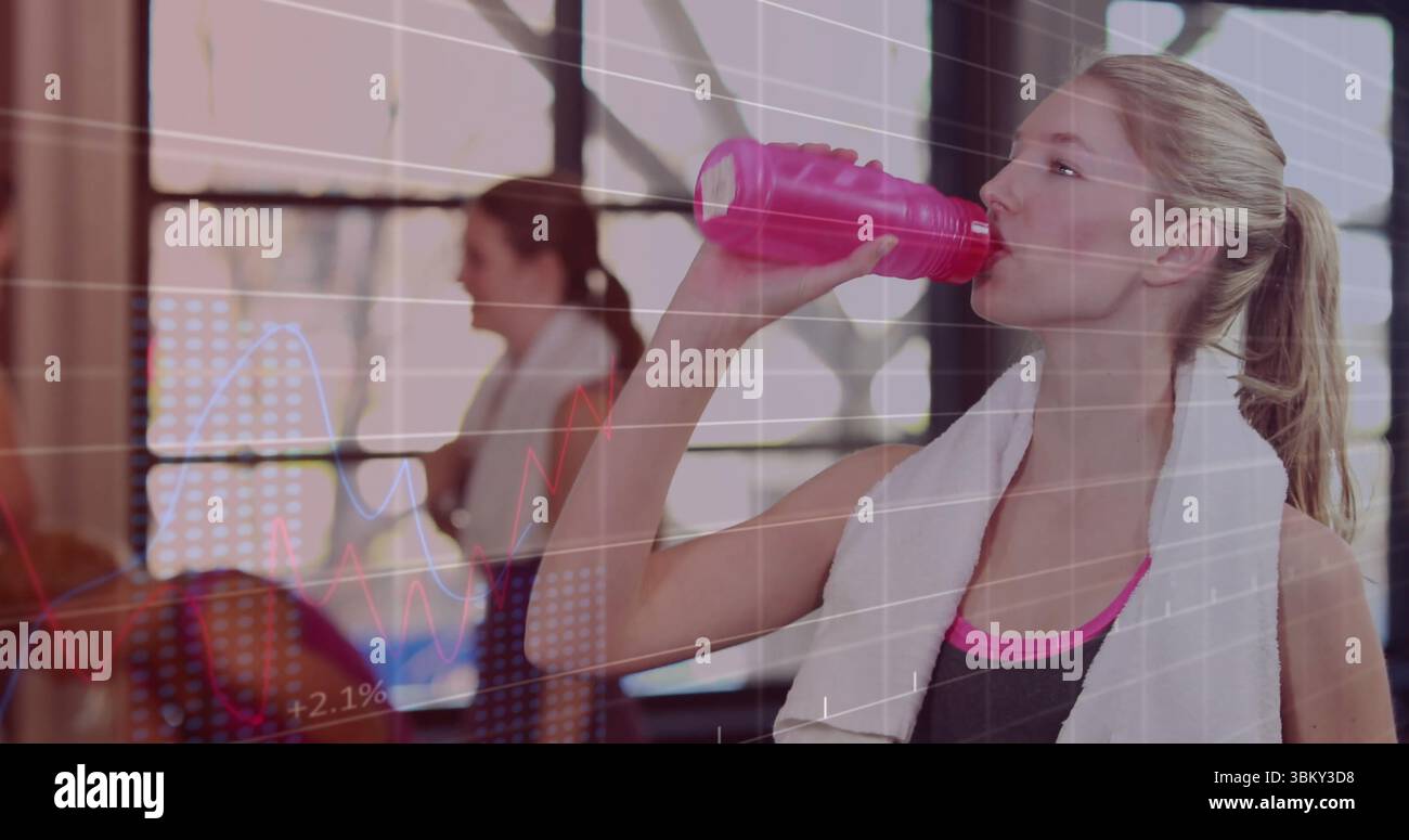 Trinkende Frau in schwarzem Sporttop mit Handtuch im Fitnessstudio, mit rosa Wasserflasche, Kopierraum Stockfoto