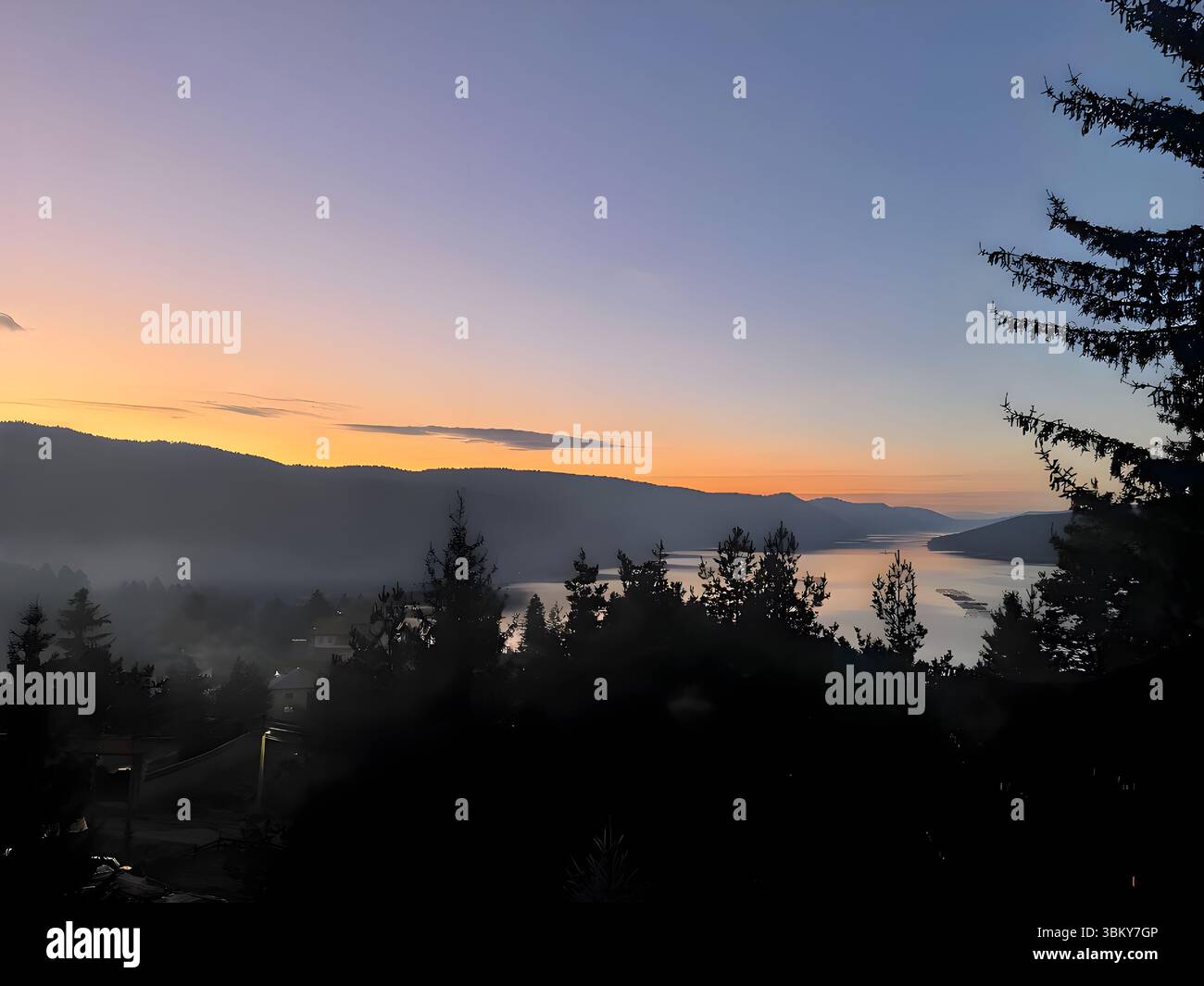 Malerischer Sonnenuntergang über dem Dospat Reservoir im Rhodopen-Gebirge, Bulgarien. Das ruhige Wasser reflektiert den pastellfarbenen Himmel, während die Sonne hinter den Hügeln untergeht. - Smartphone-aufgenommenes Stockfoto