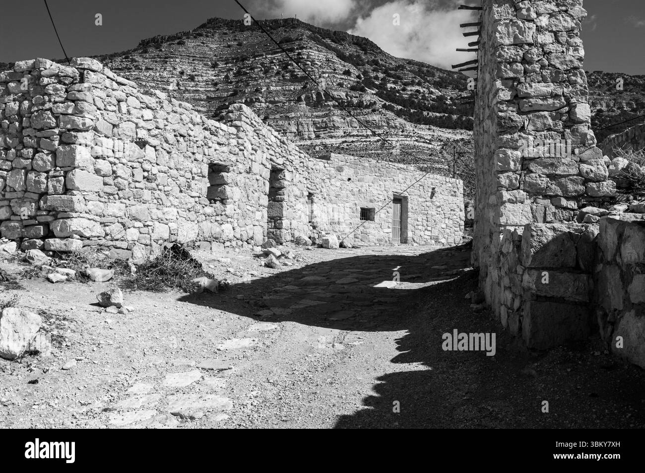 Ein Steingebäude mit einer Steinmauer und einem Steinweg. Das Gebäude ist alt und hat ein Steindach Stockfoto Ein Steingebäude mit einer Steinmauer und einem Steinweg. Das Gebäude ist alt und hat ein Steindach Stockfoto