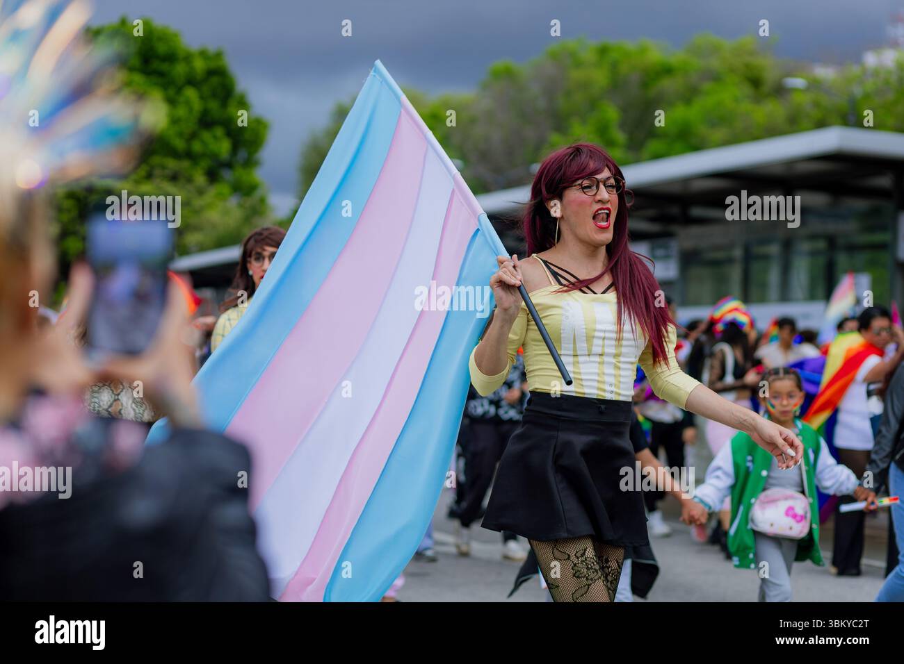 Eine Transsexuelle hebt während des LGBT+ Pride March die Transgender-Flagge mit Stolz. Das Bild stellt Empowerment, Sichtbarkeit und Geschlechts-ID dar Stockfoto