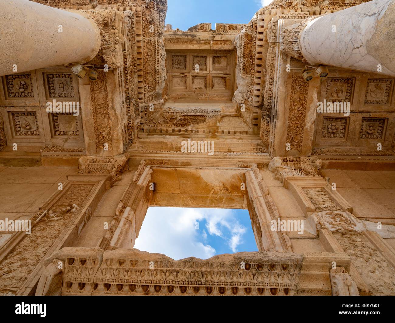Eine Niedrigwinkelaufnahme der Celsus-Bibliothek in Ephesus, Türkei, die ihre komplexen architektonischen Details und den Himmel durch ihre Öffnungen zeigt. Stockfoto