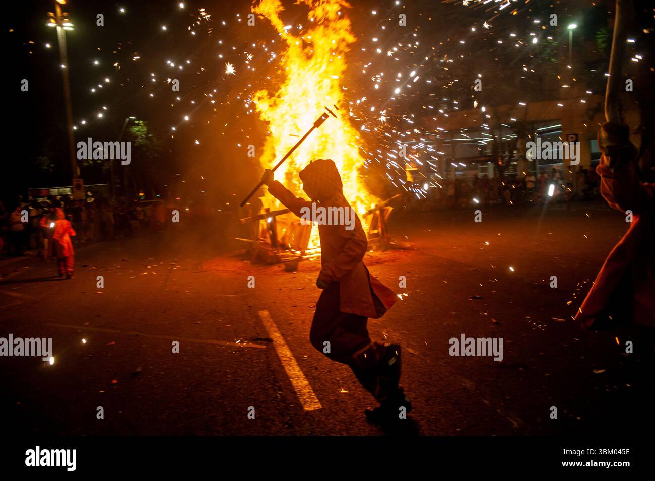Barcelona, Spanien. Juni 2025. Barcelona, Spanien: In der Nacht der Revetlla de Sant Joan (St. John's Eve) treten in den Straßen von Barcelonas Fort Pienc Menschen, die als Teufel gekleidet sind, auf und machen explodierende Pyrotechniken um ein Lagerfeuer. Als Tradition und zur Feier der Sommersonnenwende in Katalonien und den katalanisch sprechenden Gebieten wird diese Nacht mit Pyrotechnik und Feuer gefeiert. Quelle: Jordi Boixareu/Alamy Live News Stockfoto