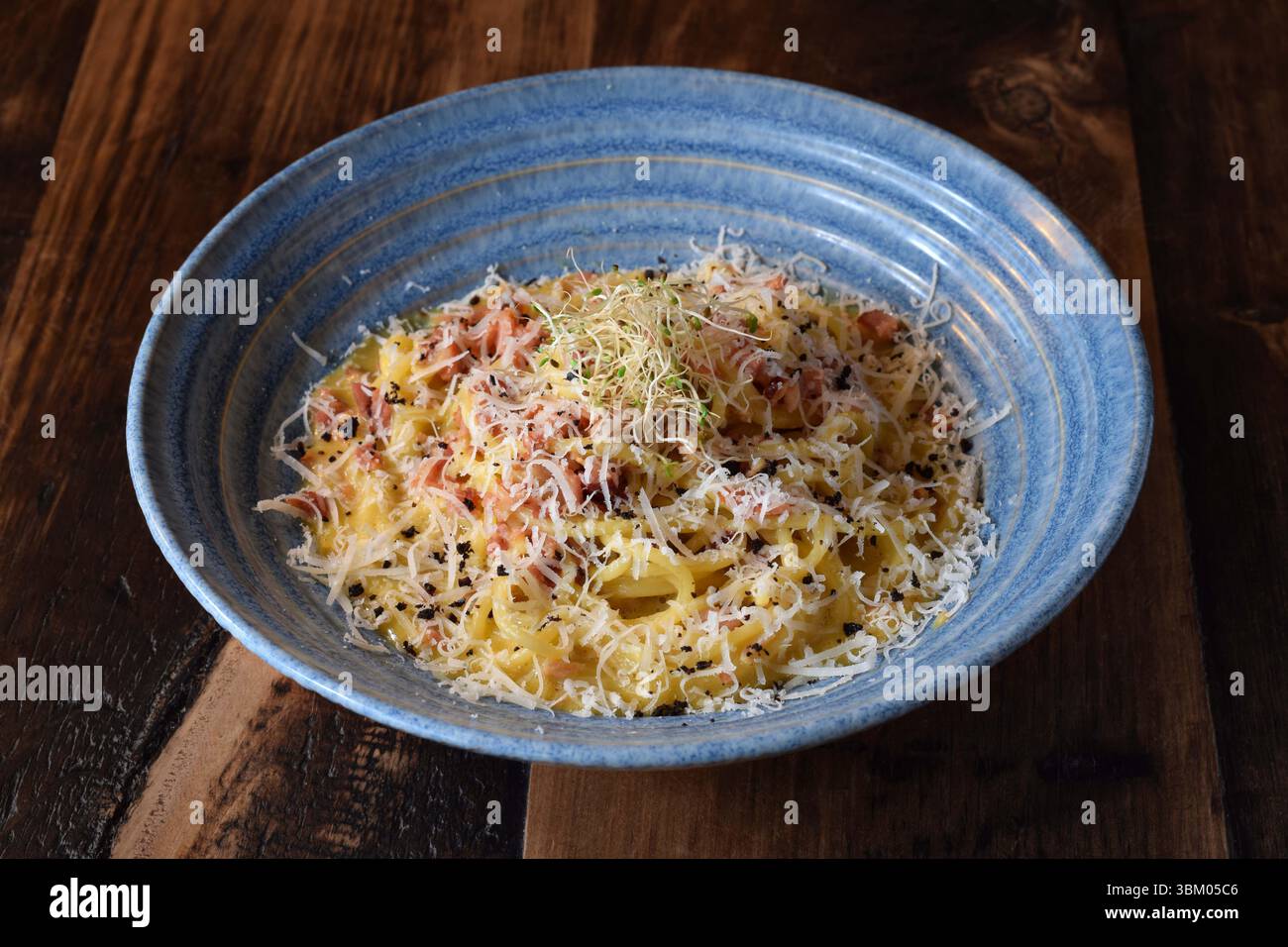 Blaue Schüssel mit Pasta Carbonara bestreut mit Parmesan Stockfoto