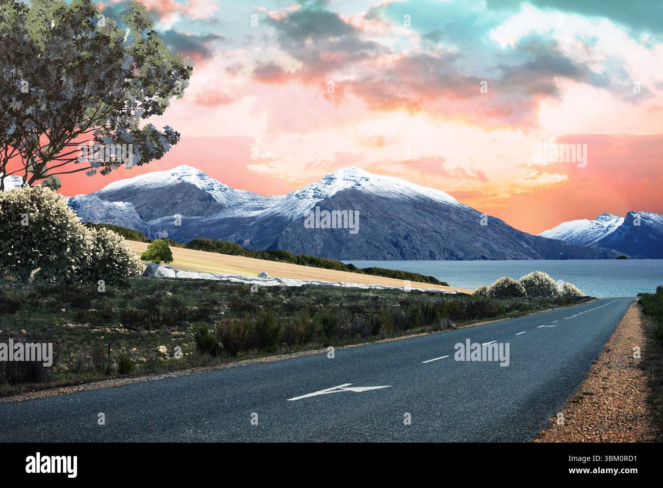Die zweispurige Asphaltstraße führt in flacher Bauweise in Richtung Sonnenuntergang über See und schneebedeckten Bergen Stockfoto