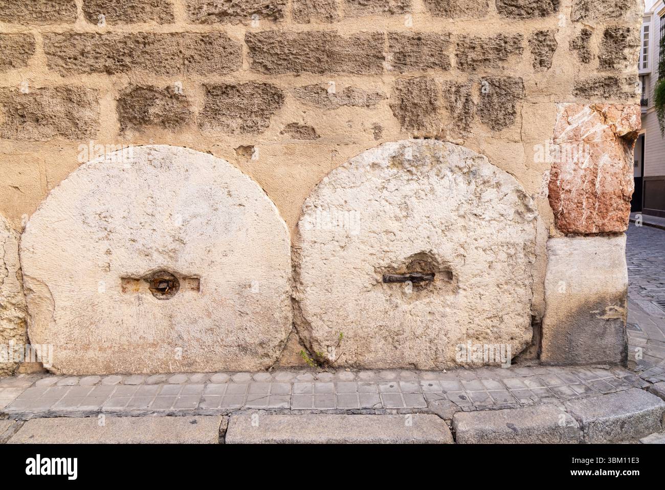 Casco Antiguo, Sevilla, Andalusien, Spanien. Steinräder wurden im Fundament eines alten spanischen Gebäudes verwendet. Stockfoto