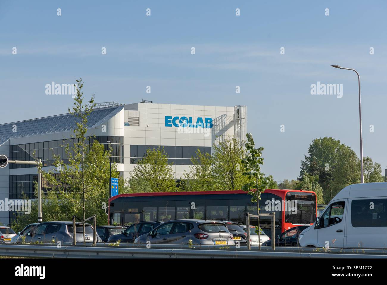 Modernes Ecolab Bürogebäude mit Logo in den Niederlanden, umgeben von Bäumen und Verkehr an einem sonnigen Tag mit klarem blauem Himmel. Oegst Stockfoto