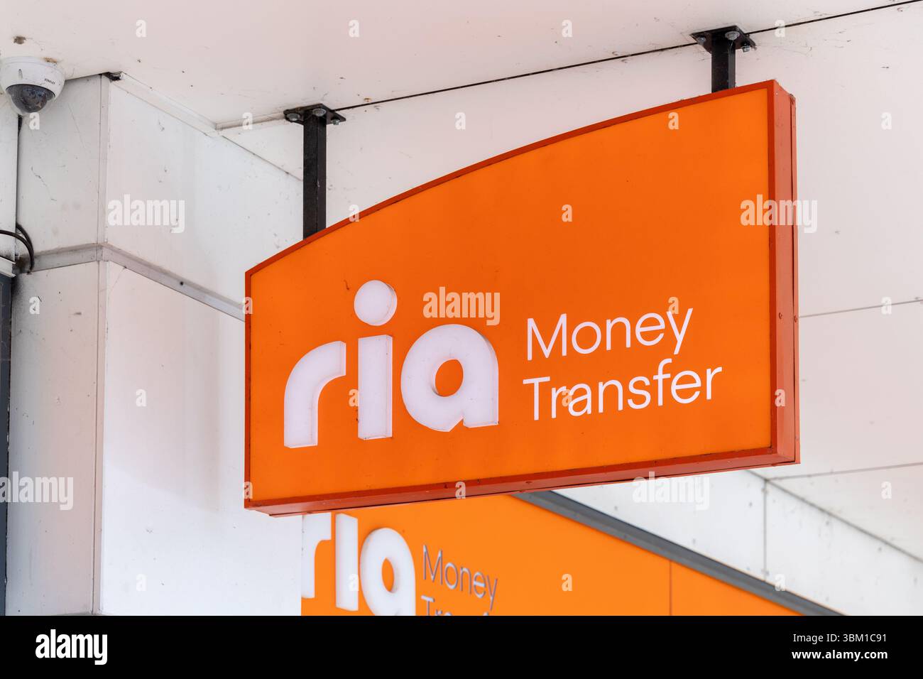 Ria Money Transfer Schild an der Außenseite eines Finanzgeschäfts mit leuchtend orangefarbenem Branding, an einer modernen Gebäudefassade bei Tageslicht montiert. Stockfoto