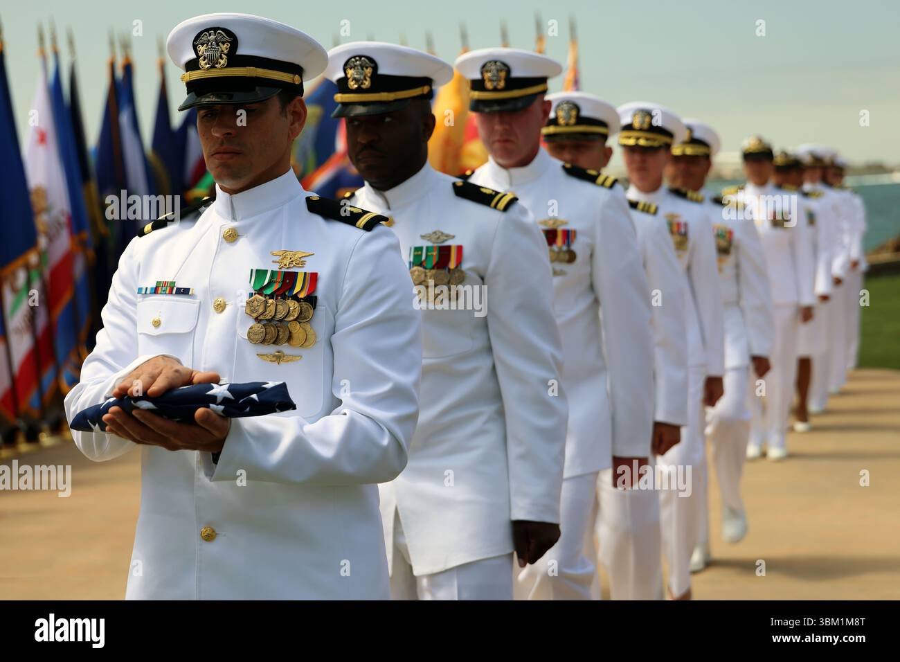 Seeleute mit der Flagge marschieren in Formation, um die zeremonielle Übergabe der Flagge während einer Ruhestandszeremonie für Kapitän Aric und Rachel Baudek am Naval Base Point Loma, San Diego, am 20. Juni 2025 durchzuführen. Die Baudeks gingen nach 49 Jahren als Navy Krankenschwestern in den Ruhestand, zuletzt mit dem Expeditionary Medicine Systems im Navy Medicine Readiness and Training Command Camp Pendleton. (Foto der US Navy von Arsenio R. Cortez Jr.) Stockfoto