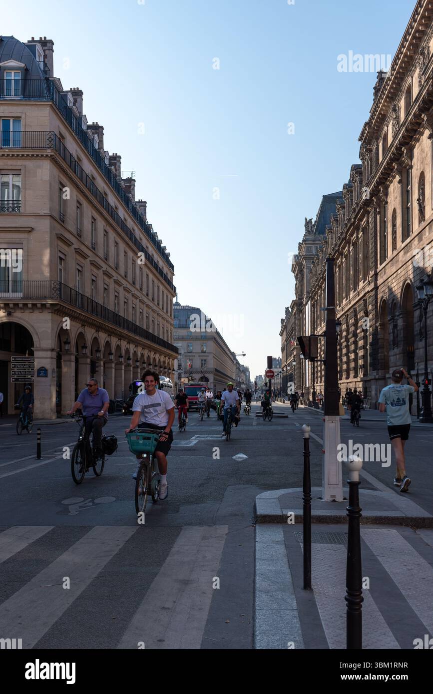 Radfahrer auf der Rue de Rivoli im 1. Arrondissement von Paris an einem sonnigen Morgen. Straßenszene. Wunderschöne haussmannische Apartments. Radfahren in Paris Stockfoto