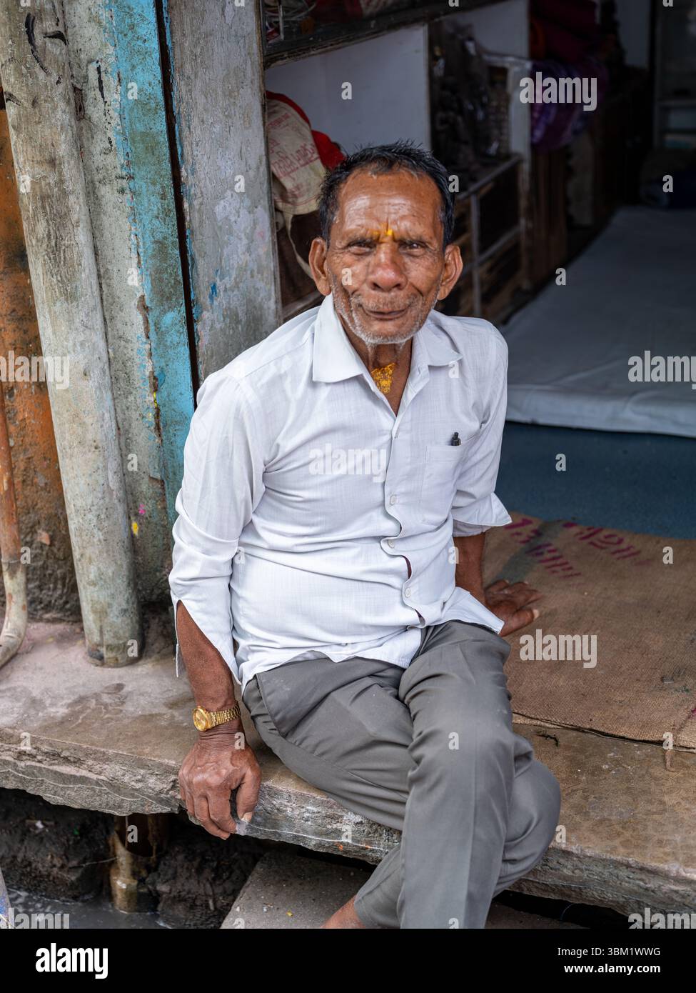 Indien, Jaipur, 14. März 2025. Porträt eines älteren Indianers mit heiligen Stirnmarkierungen, der vor einem traditionellen Geschäft in der Altstadt von Jaipur sitzt Stockfoto