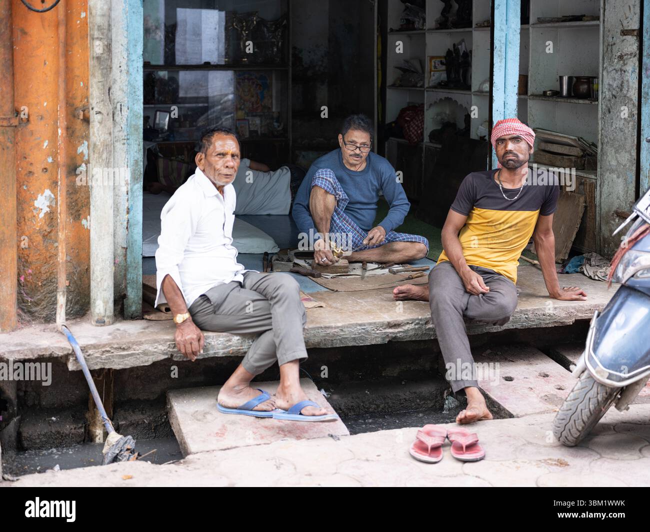 Indien, Jaipur, 14. März 2025. Drei indische Männer, die sich während eines Holi Festivals in der Altstadt entspannen und sich unterhalten, eine offene Straßenszene. Stockfoto