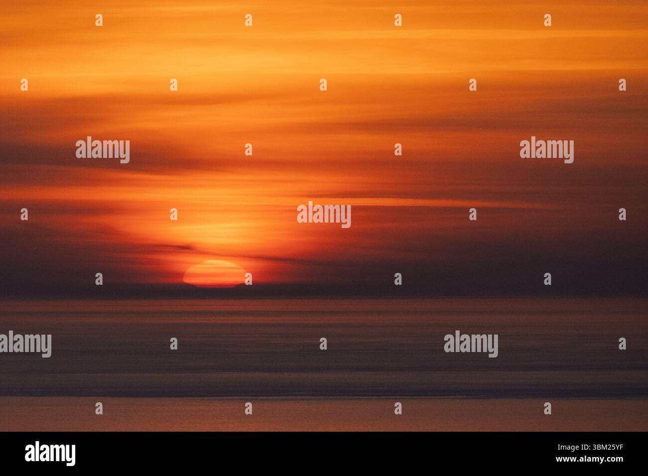 Sonnenaufgang über dem Meer mit Wolken und Mustern. Stockfoto