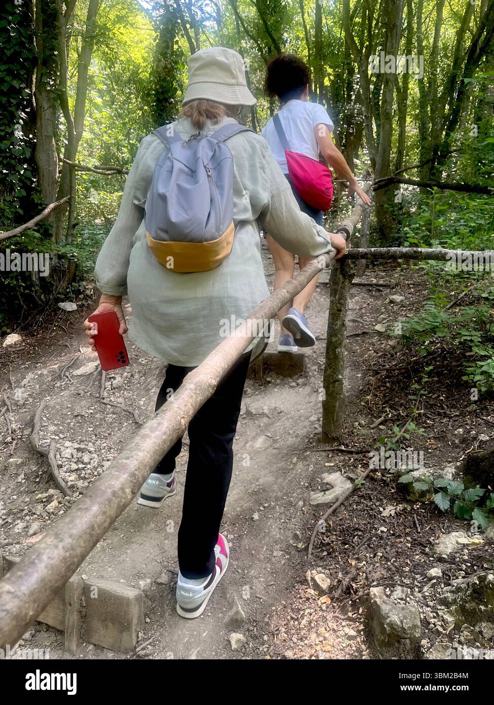 Weibliche Wanderer klettern auf einem steilen Waldweg an den Krushuna Wasserfällen, Bulgarien, und genießen ein aktives Outdoor-Erlebnis in üppiger Karstlandschaft - Smartphone-aufgenommenes Stockfoto
