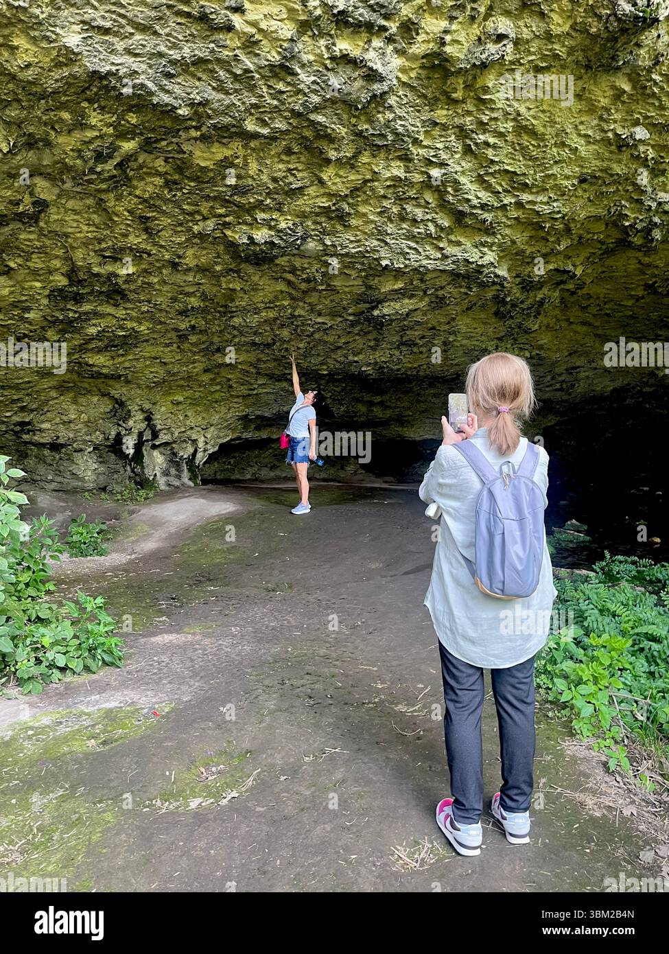 Besucher machen Fotos am Eingang der Urushka-Maara-Höhle in der Nähe der Krushuna-Wasserfälle, einem beliebten Wander- und Karstforschungsort in Bulgarien, dem Balkan Stockfoto
