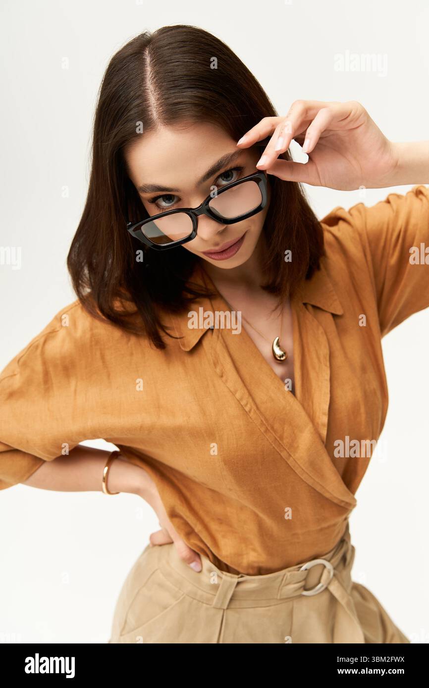 Eine junge, schöne Frau zeigt ihren einzigartigen Sinn für Mode in stilvoller Kleidung und Brille. Stockfoto