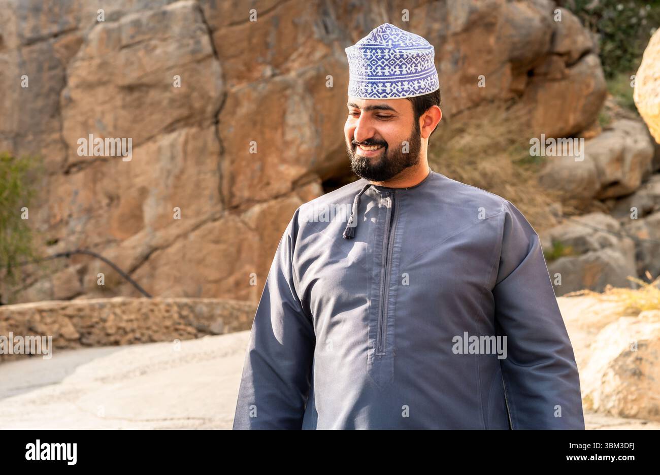 Misfat Al Abriyeen, Oman - 11. Februar 2020: Porträt eines lächelnden omanischen Mannes in traditionellem blauem Dschadscha und besticktem omanischen Kuma. Stockfoto