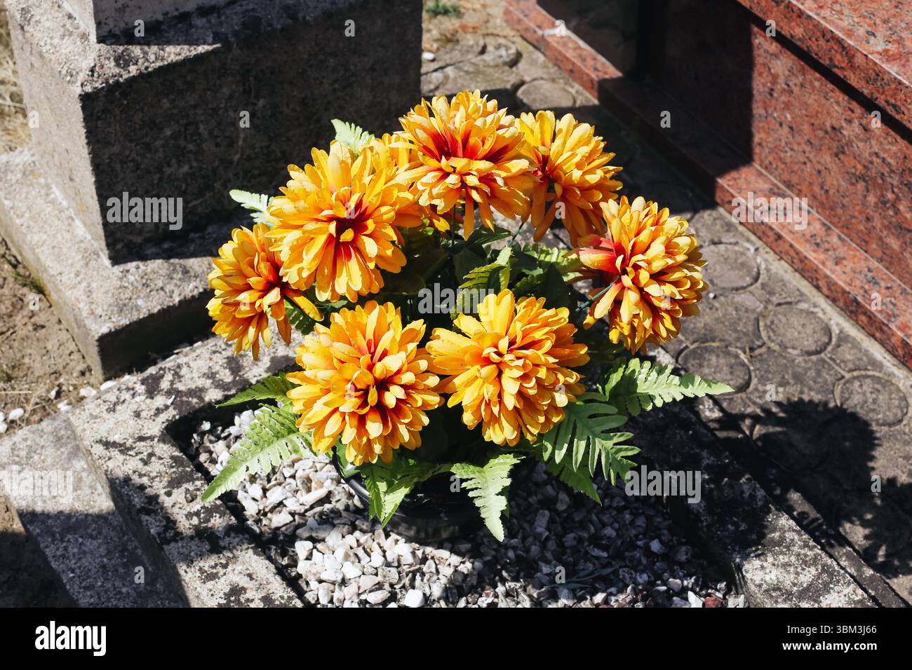 Friedhofsblumen auf dem Grab. Heller Ringelblumenstrauß. Trauerfeier in lebendigen Farben. Respekt und Erinnerung. Traditionelle Grabdekoration. Stockfoto