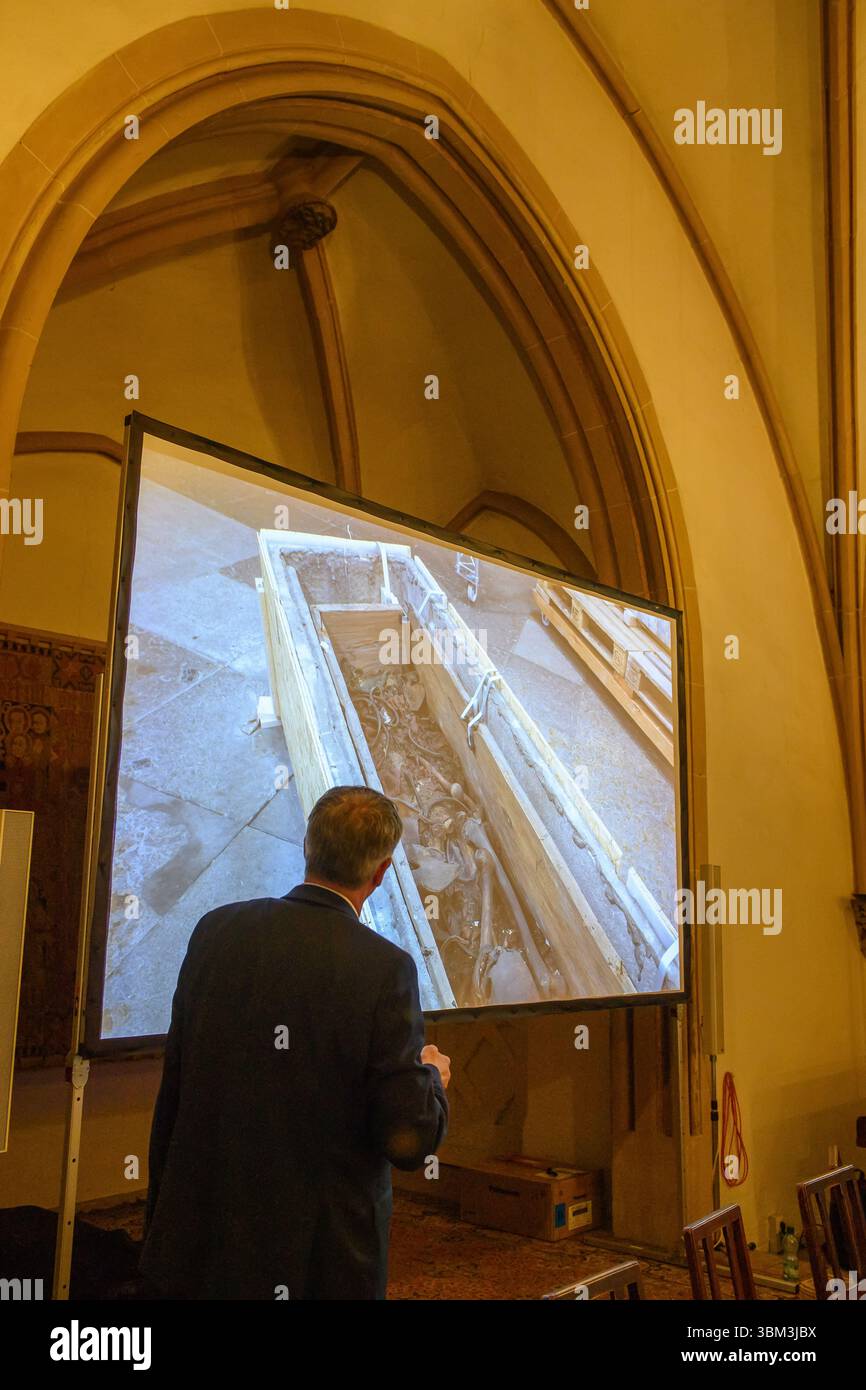 24. Juni 2025, Sachsen-Anhalt, Magdeburg: Donat Wehner (l) vom Landesamt für Denkmalpflege und Archäologie Sachsen-Anhalt erklärt Medienvertretern in der Sakristei des Magdeburger Doms mit Hilfe einer Live-Videoübertragung aus dem Inneren des Gehäuses um das Grab Ottos des Großen den Schaden in der Holzkiste, in der Knochen zu sehen sind. Seit Januar führen das Landesamt für Denkmalpflege und Archäologie und die Kulturstiftung Sachsen-Anhalt Untersuchungen zur Erhaltung des Denkmals durch. Die Resu Stockfoto