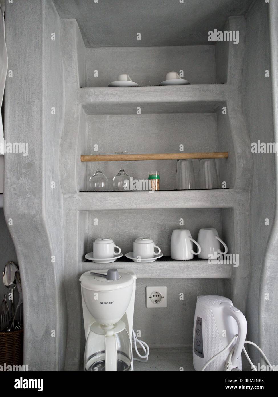 Moderne Küche in neutralen Farben mit sauberen Regalen und minimalistischen Küchenutensilien in dezentem Licht. Stockfoto