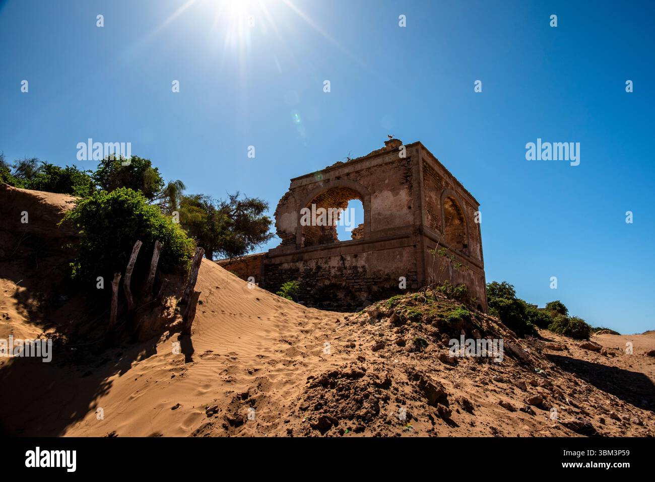 Ruinen einer alten Wohnung zwischen den einsamen Dünen der Strände mit blauem Himmel und grünen Bäumen in Essaouira in Marokko Stockfoto