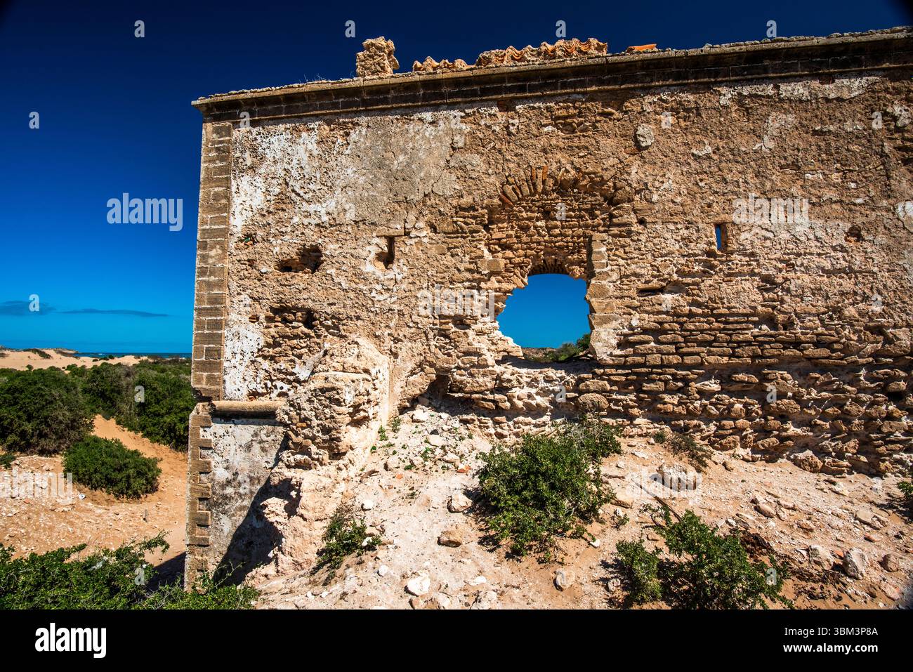 Ruinen einer alten Wohnung zwischen den einsamen Dünen der Strände mit blauem Himmel und grünen Bäumen in Essaouira in Marokko Stockfoto