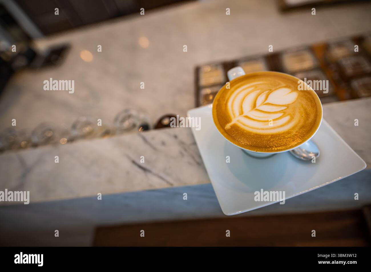 Latte Art auf Marmortheke in elegantem Café mit weichem, unscharfem Hintergrund, stilvolle Innenszene im Café zur Entspannung, modernes Getränkekonzept Stockfoto