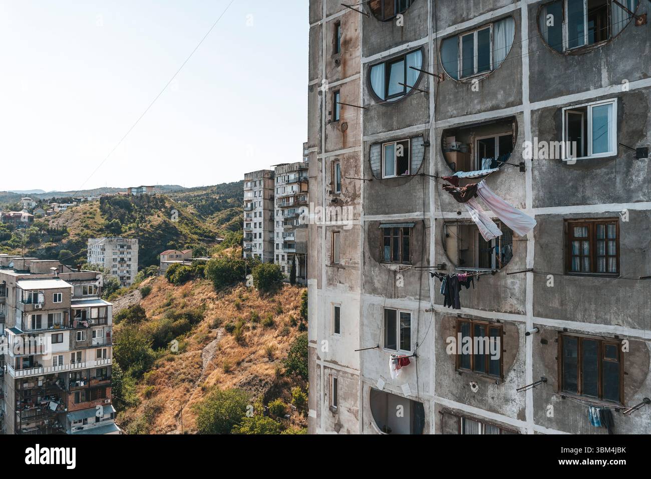 Fotos von alten Wohngebäuden aus Betonplatten aus den 1970er Jahren in Tiflis, Georgien. Diese ikonischen Beispiele brutalistischer Architektur aus der Sowjetzeit spiegeln den krassen, utilitaristischen Stil jener Zeit wider. Rohtexturen, sich wiederholende Geometrien und verwitterte Fassaden sprechen vom historischen und sozialen Kontext der Stadtentwicklung während der Sowjetzeit. Stockfoto