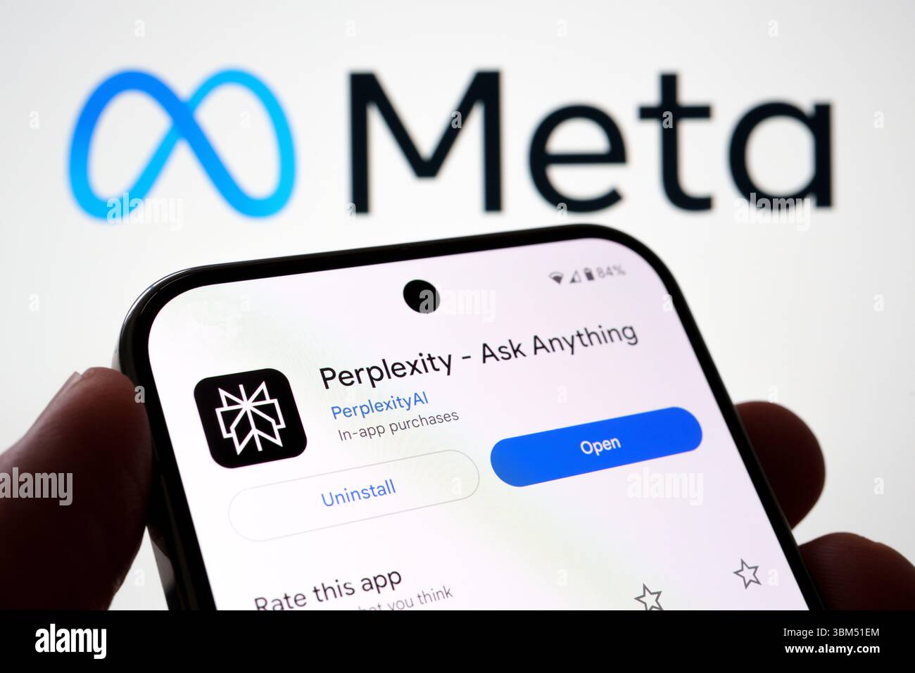 Der Bildschirm der Perplexity-KI-Software wird in der Hand gehalten, hinter dem Meta-Firmenlogo. Stafford, Großbritannien, 24. Juni 2025 Stockfoto