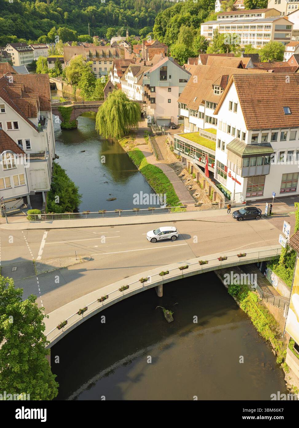 Ein Auto fährt über eine Brücke, die einen Fluss überquert, in einer charmanten urbanen Landschaft mit grüner Umgebung, Deer E, Carsharing, Elektroauto, Calw, Schwarz Stockfoto