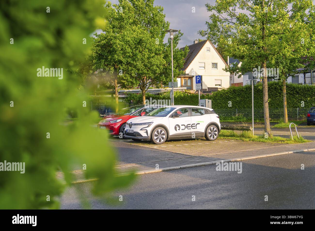 Ein Elektroauto parkt bei Sonnenuntergang auf einer ruhigen Straße umgeben von Bäumen, Hirsch E, Carsharing, Elektroauto, Calw, Schwarzwald Stockfoto