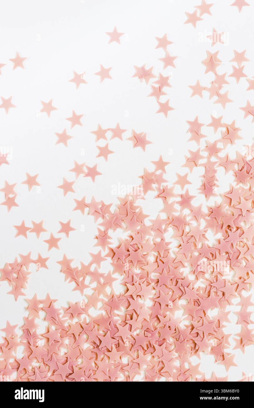 Pastellrosa Konfetti-Sterne auf weißem Hintergrund. Feiertagsparty-Konzept Stockfoto