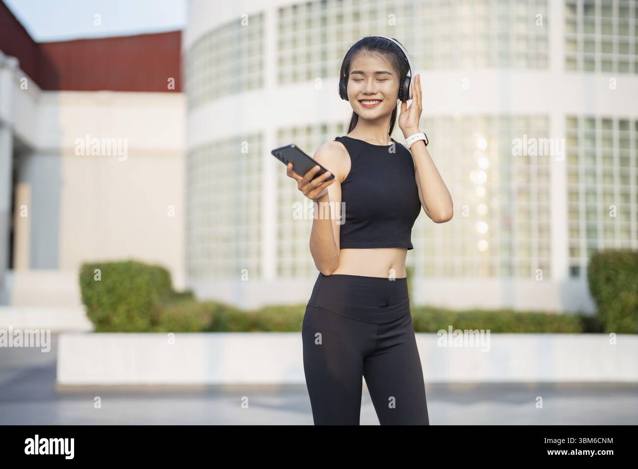 Happy Active Healthy asian Woman hört Musik mit Kopfhörern für geistige Gesundheit Hören von Audio für Laufen Inspiration Stockfoto