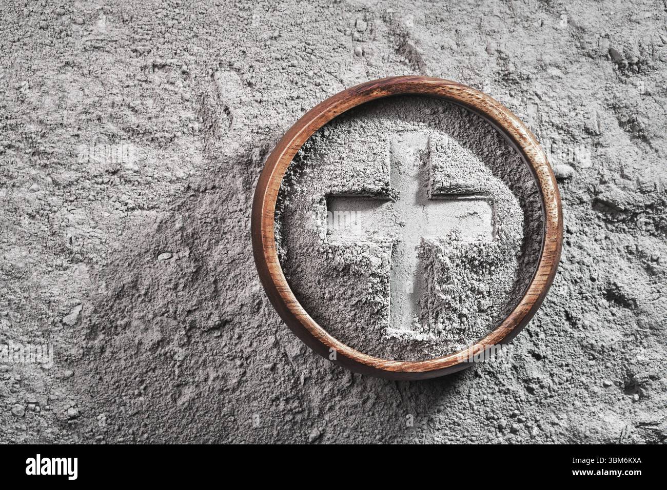 Kreuzabdruck in grauer Eschenschale auf Aschenhintergrund. Aschenmittwoch Stockfoto