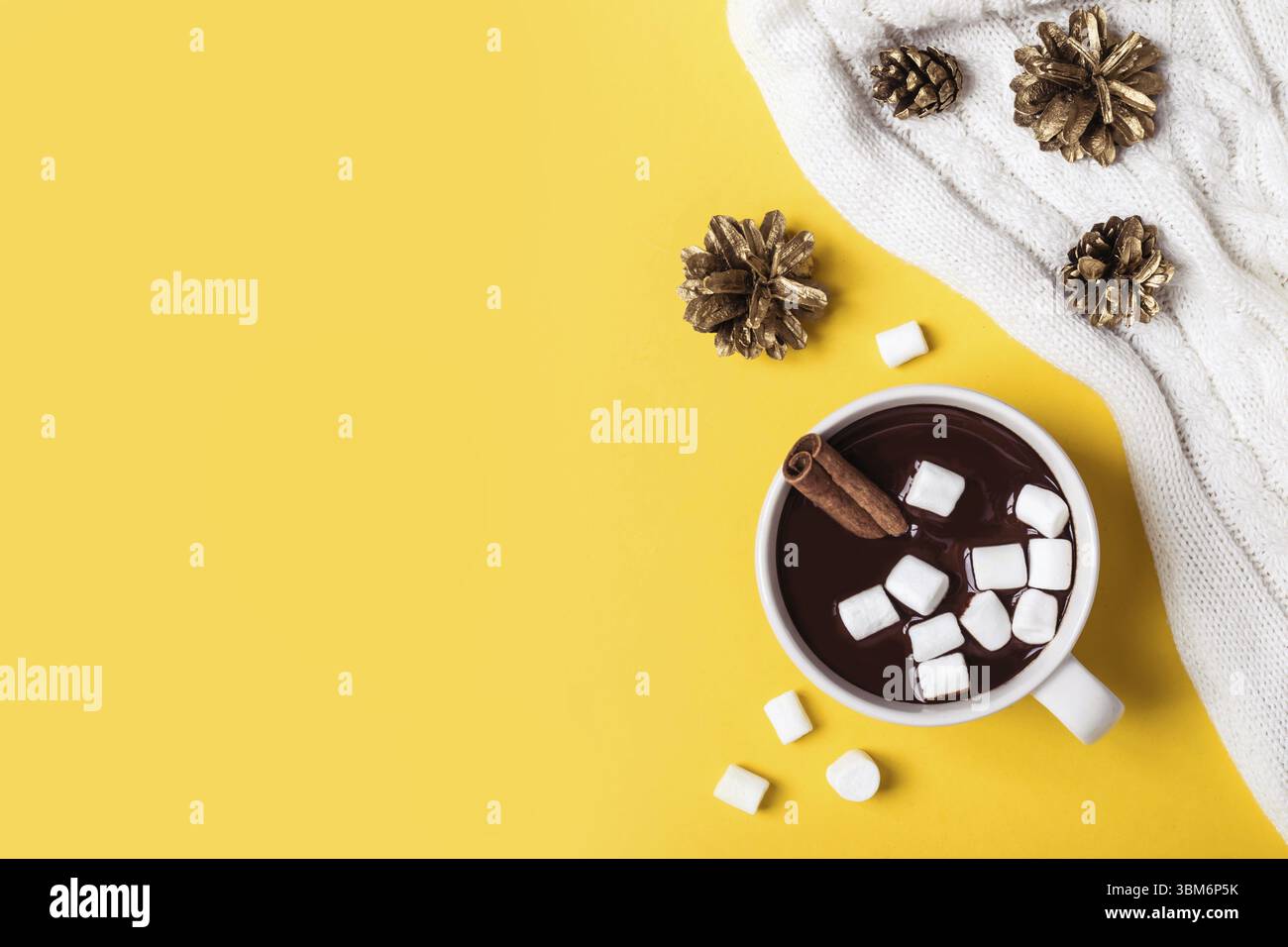 Heiße Schokoladentasse mit Zimt und Marshmallow auf gelbem Hintergrund. Warmes Weihnachtsgetränk im Winter Stockfoto