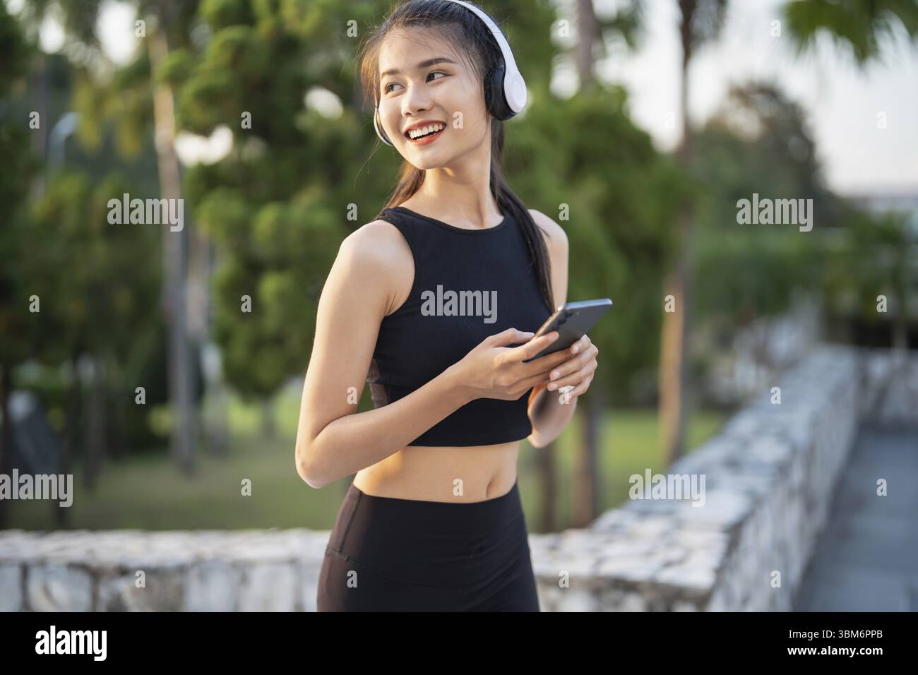 Happy Active Healthy asian Woman hört Musik mit Kopfhörern für geistige Gesundheit Hören von Audio für Laufen Inspiration Stockfoto