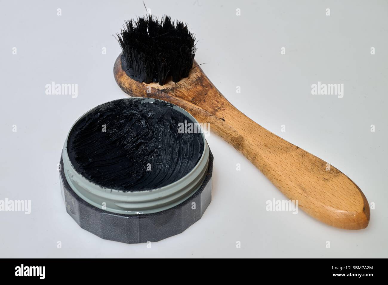Schwarze schuhpolitur und schmutzige Bürste auf weißem Hintergrund Stockfoto
