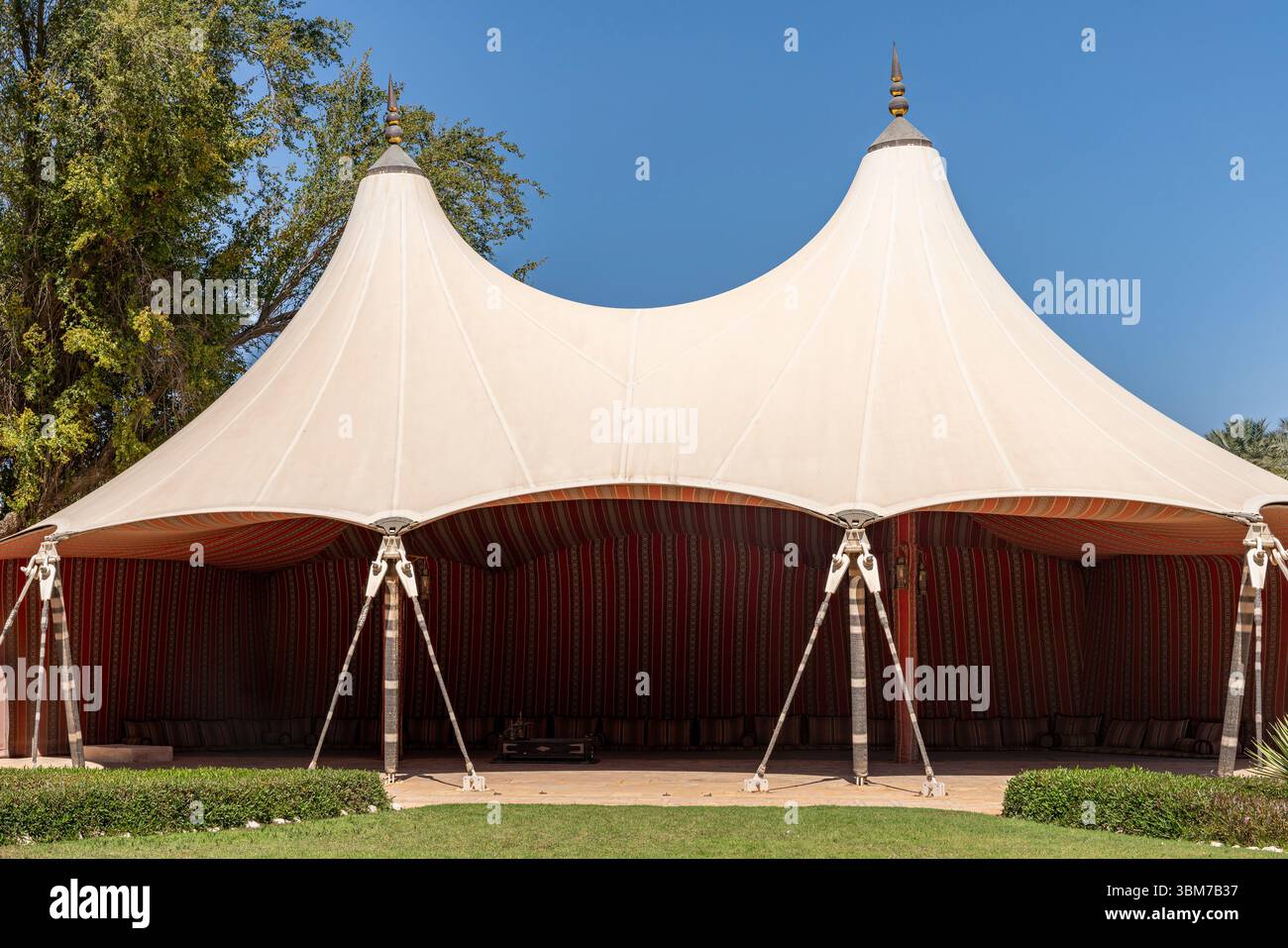 Großes weißes Zelt mit spitzem Dach und offenen Seiten in einem Garten, Lage Al Ain Palace Museum, Vereinigte Arabische Emirate. Stockfoto