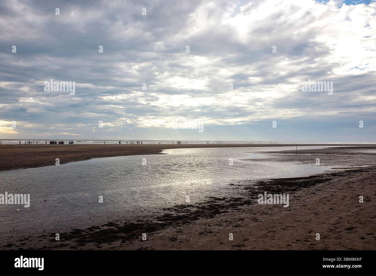 Der weite Blick auf eine Lagune an der Küste spiegelt den bewölkten Himmel wider, wenn die Dämmerung sich nähert. Stockfoto