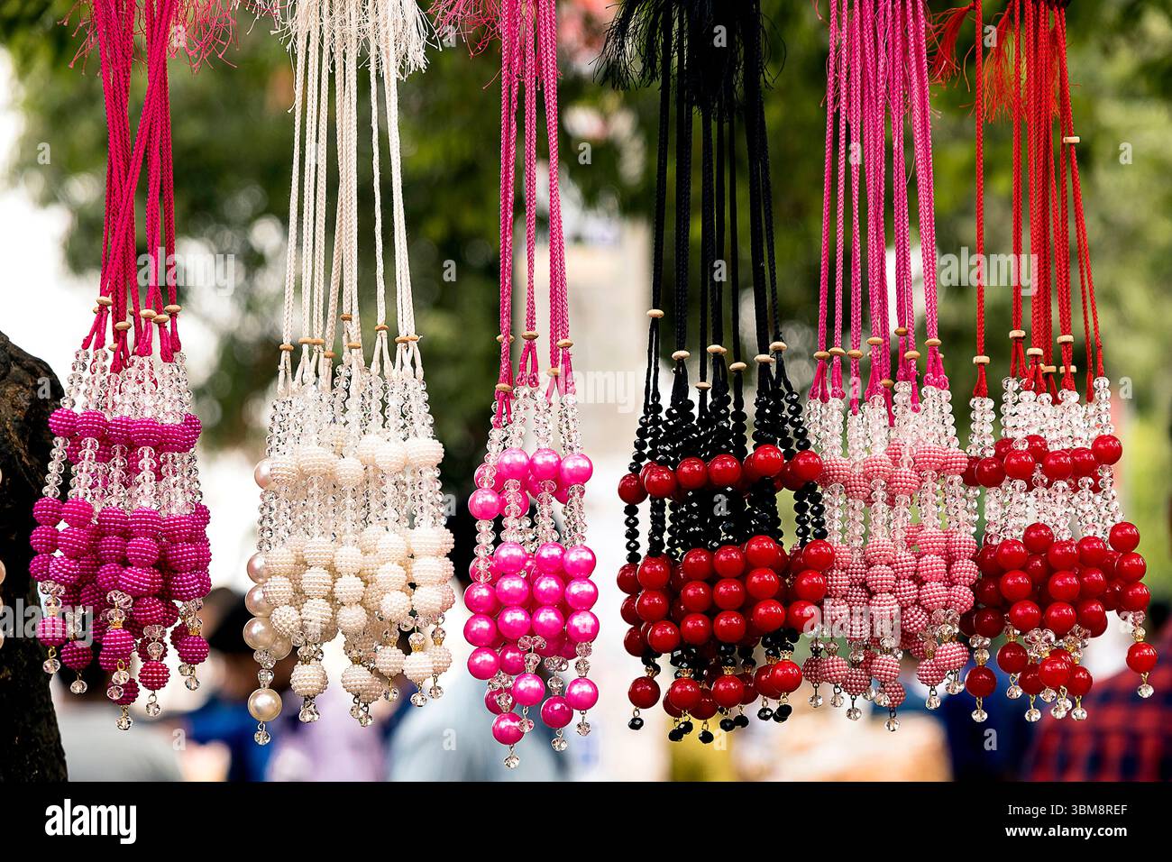 Handwerker präsentieren lebendige handgefertigte Perlenketten in verschiedenen Farben und Stilen, die Käufer auf einem geschäftigen Markt anziehen. Stockfoto Handwerker präsentieren lebendige handgefertigte Perlenketten in verschiedenen Farben und Stilen, die Käufer auf einem geschäftigen Markt anziehen. Stockfoto