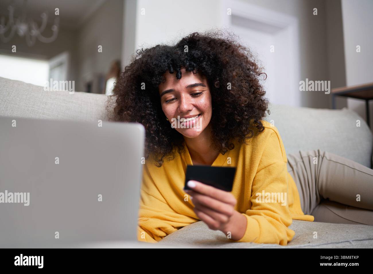 Lächelnde Frau beim Online-Shopping mit Kreditkarte auf bequemer Couch Stockfoto