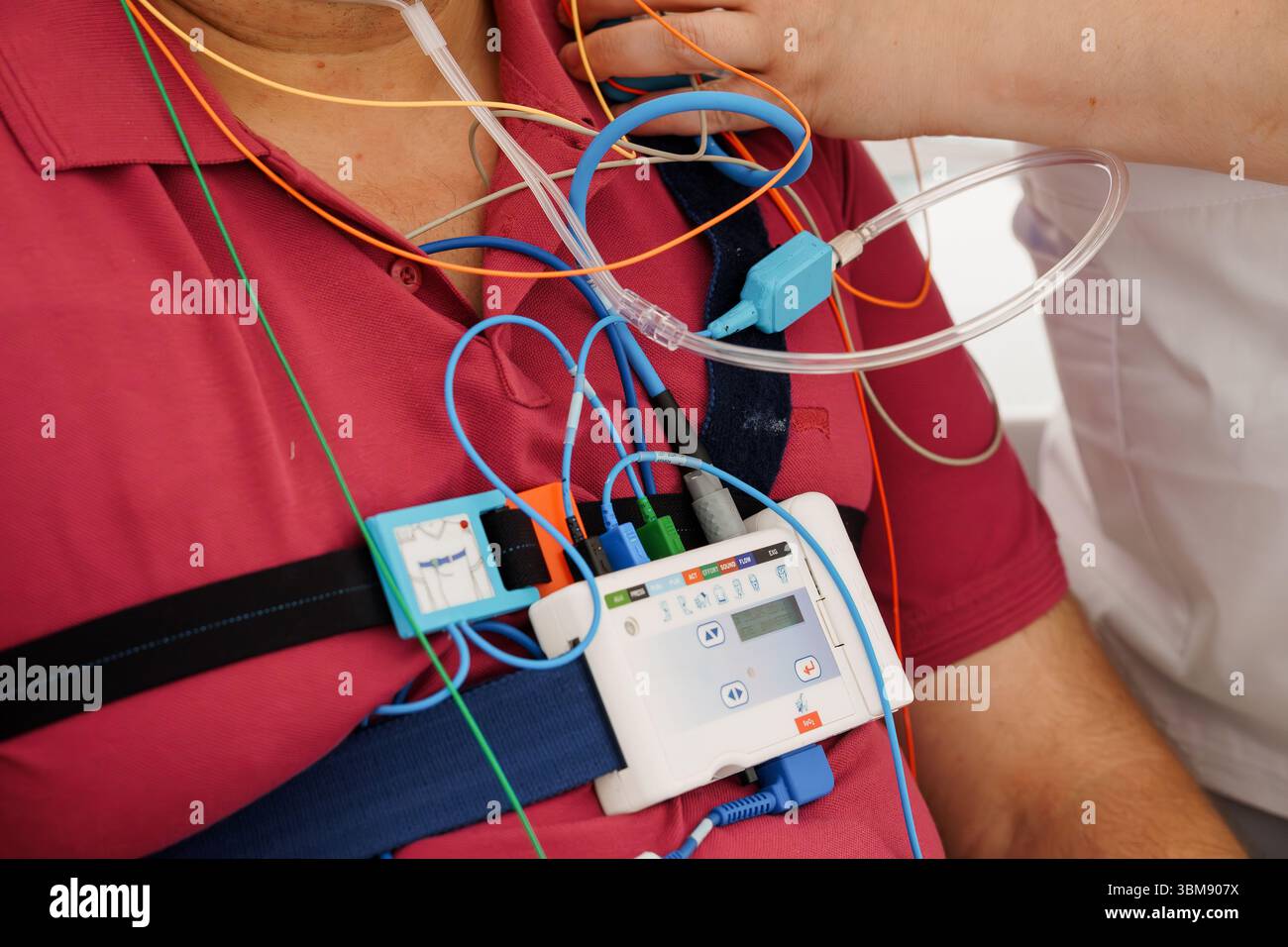 Patientenüberwachung mit Holter-Schreiber: Medizinisches EKG-Herzfrequenzmessgerät, das mit Drähten und Bildschirm an der Brust befestigt ist Stockfoto